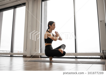 Woman balancing on one leg and keeping hands in namaste 101877289