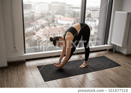 Slim fitness woman bending body to bare feet in studio Slim fitness woman bending body to bare feet in studio 101877328