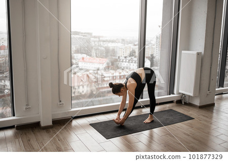 Slim fitness woman bending body to bare feet in studio Slim fitness woman bending body to bare feet in studio 101877329