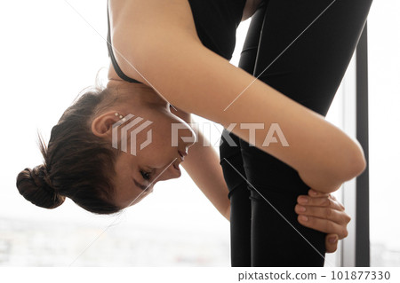 Slim woman bending body with head to knees in studio Slim woman bending body with head to knees in studio 101877330