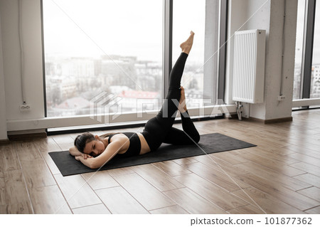 Woman in sportswear stretching legs on yoga mat Woman in sportswear stretching legs on yoga mat 101877362