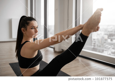 Fitness woman flexing body while sitting in splits indoors Fitness woman flexing body while sitting in splits indoors 101877375