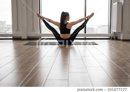 Fitness woman flexing body while sitting in splits indoors Fitness woman flexing body while sitting in splits indoors 101877377