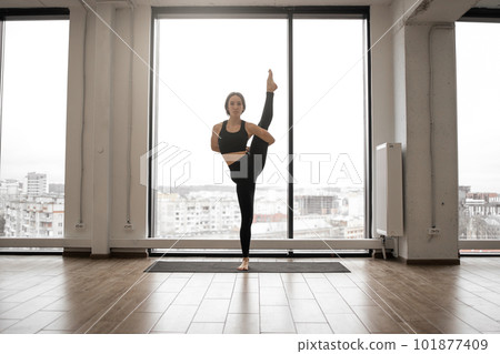 Female yogi performing variation of trivikramasana posture 101877409