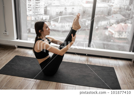 Fit young female training navasana pose indoors 101877410