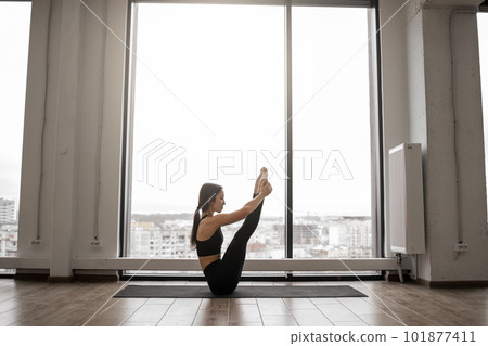 Fit young female training navasana pose indoors 101877411