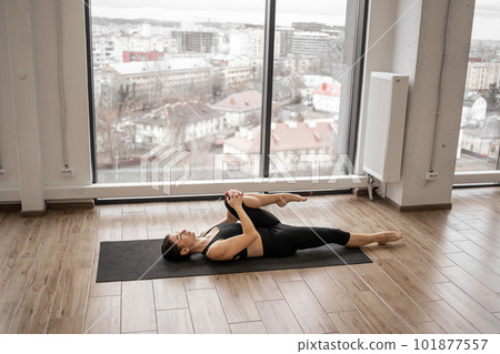 Woman getting into Knees-to-Chest Pose in fitness studio Woman getting into Knees-to-Chest Pose in fitness studio 101877557