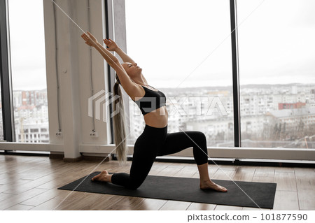 Adult female achieving High Lunge Pose in meditation room 101877590