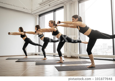 Women balancing in Warrior III pose in yoga studio Women balancing in Warrior III pose in yoga studio 101877648
