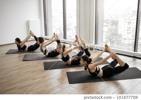 Females holding Bow Pose in sports club studio Females holding Bow Pose in sports club studio 101877799