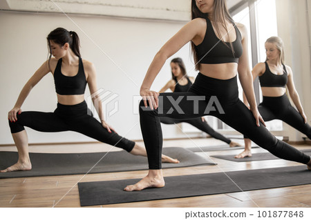 Ladies in sportswear doing warm-up for yoga posture indoors Ladies in sportswear doing warm-up for yoga posture indoors 101877848