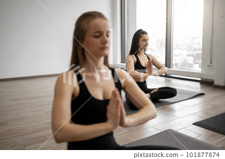 Women exercising Padmasana on yoga class in meditation room Women exercising Padmasana on yoga class in meditation room 101877874