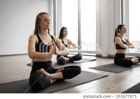 Ladies holding yoga position with namaste in studio room Ladies holding yoga position with namaste in studio room 101877875