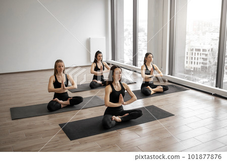 Females practicing lotus pose with namaste in studio Females practicing lotus pose with namaste in studio 101877876