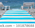 close-up of striped beach path between sun loungers on pebble beach leading to blue sea. summer holiday backdrop. selective focus 101878688