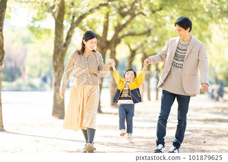 A family walking hand in hand along a tree-lined street 101879625