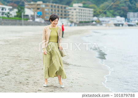 Middle-aged woman walking on the beach Middle-aged woman walking on the beach 101879788