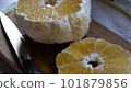 A cross section of a summer mandarin orange being cut on a cutting board 101879856