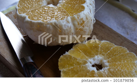 A cross section of a summer mandarin orange being cut on a cutting board 101879856