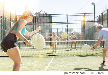 Young sporty woman playing padel game in court on sunny day Young sporty woman playing padel game in court on sunny day 101880285