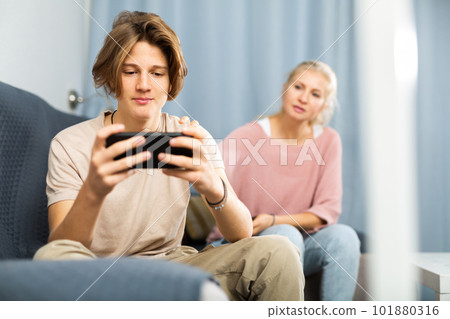 Teen boy with smartphone not paying attention to upset mother Teen boy with smartphone not paying attention to upset mother 101880316