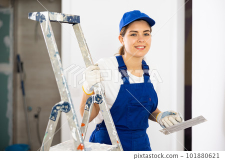 Portrait of young woman builder with trowel standing in apartment 101880621