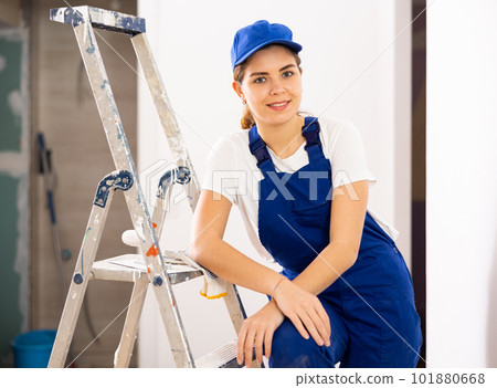 Positive young female builder in blue workwear standing at construction site Positive young female builder in blue workwear standing at construction site 101880668