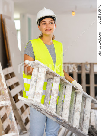 Portrait of woman in protective yellow vest and hard hat in room being renovated 101880670