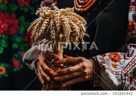 Ukrainian woman in authentic costume with Didukh on colorful ornaments carpet. Ukrainian woman in authentic costume with Didukh on colorful ornaments carpet. 101881442