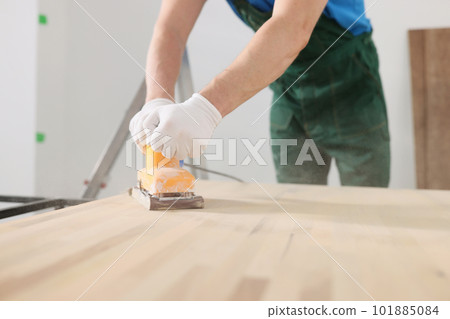 Skilled carpenter polishes wooden surface of office table 101885084