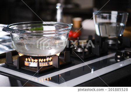 Water boiling in borosilicate glass casserole on gas stove 101885528