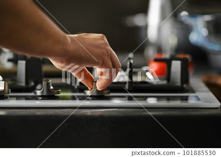Hand switching on gas on a stove Hand switching on gas on a stove 101885530