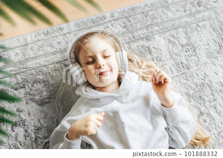 Little girl listening music lying on the floor 101888332