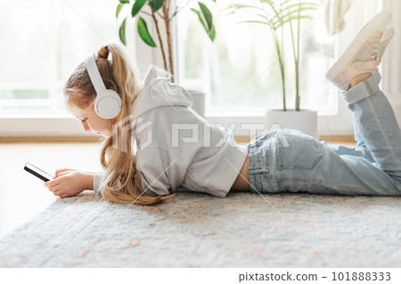 Little girl listening music lying on the floor Little girl listening music lying on the floor 101888333