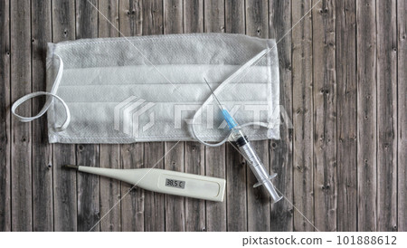 Sterile medical masks, vaccine vial and glass thermometer on a wooden background with copy space 101888612