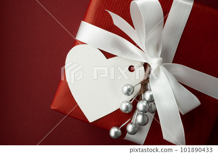 Empty white heart-shaped gift tag on a red gift box with a white ribbon. Space for your text. Valentine's Day Card Empty white heart-shaped gift tag on a red gift box with a white ribbon. Space for your text. Valentine's Day Card 101890433