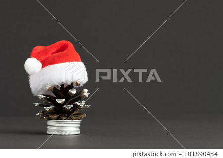 Pine cone in Santa's hat on gray background. Idea of alternative Christmas tree. Space for yout text. Pine cone in Santa's hat on gray background. Idea of alternative Christmas tree. Space for yout text. 101890434