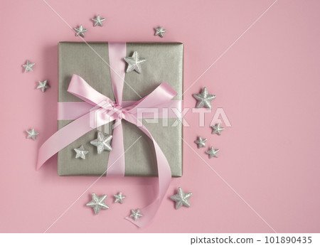 Silver gift box with pink ribbon, white empty gift tag and silver stars on pink background. Space for your text. 101890435
