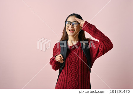 Smiling Asian female college student looking away from camera with hand above her eye 101891470