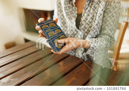 Fortune teller with tarot cards on table near burning candle.Tarot cards spread on table with magic herbs and palo santo aroma sticks. Forecasting concept 101891768