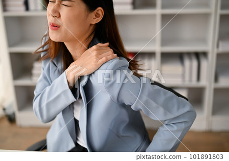 Unwell Asian businesswoman suffering from shoulder pain while working in the office Unwell Asian businesswoman suffering from shoulder pain while working in the office 101891803