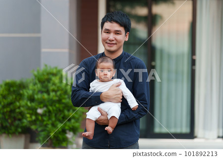 happy father holding with newborn baby while standing in front of house 101892213