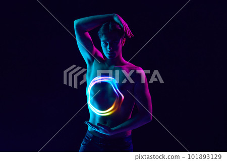 Power. Handsome young man posing shirtless with digital neon filter reflection on body over dark purple background in neon light Power. Handsome young man posing shirtless with digital neon filter reflection on body over dark purple background in neon light 101893129