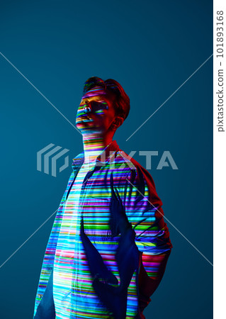 Innovative vision. Handsome young man in casual clothes standing with digital neon filter reflection with multicolored stripes over blue background Innovative vision. Handsome young man in casual clothes standing with digital neon filter reflection with multicolored stripes over blue background 101893168