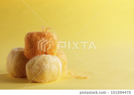 Image of a ball of yellow mohair yarn taken against a yellow background Image of a ball of yellow mohair yarn taken against a yellow background 101894478