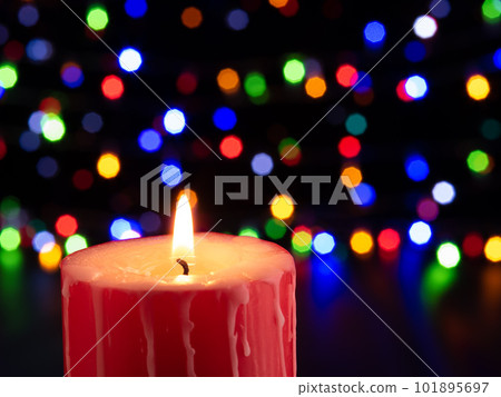 festive candle on a black background with colorful lights 101895697