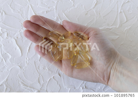 Large yellow capsules with Omega 3 or fish oil in a woman's hand, close-up. Health and wellness, self-medication Large yellow capsules with Omega 3 or fish oil in a woman's hand, close-up. Health and wellness, self-medication 101895765