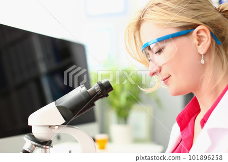 Woman scientist in glasses conducts research through microscope in chemical laboratory Woman scientist in glasses conducts research through microscope in chemical laboratory 101896258