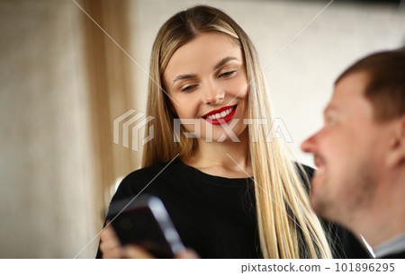 Woman hairdresser looks at smartphone client with male hairstyle Woman hairdresser looks at smartphone client with male hairstyle 101896295