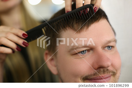 Hairdresser cuts hair with scissors and black comb 101896299